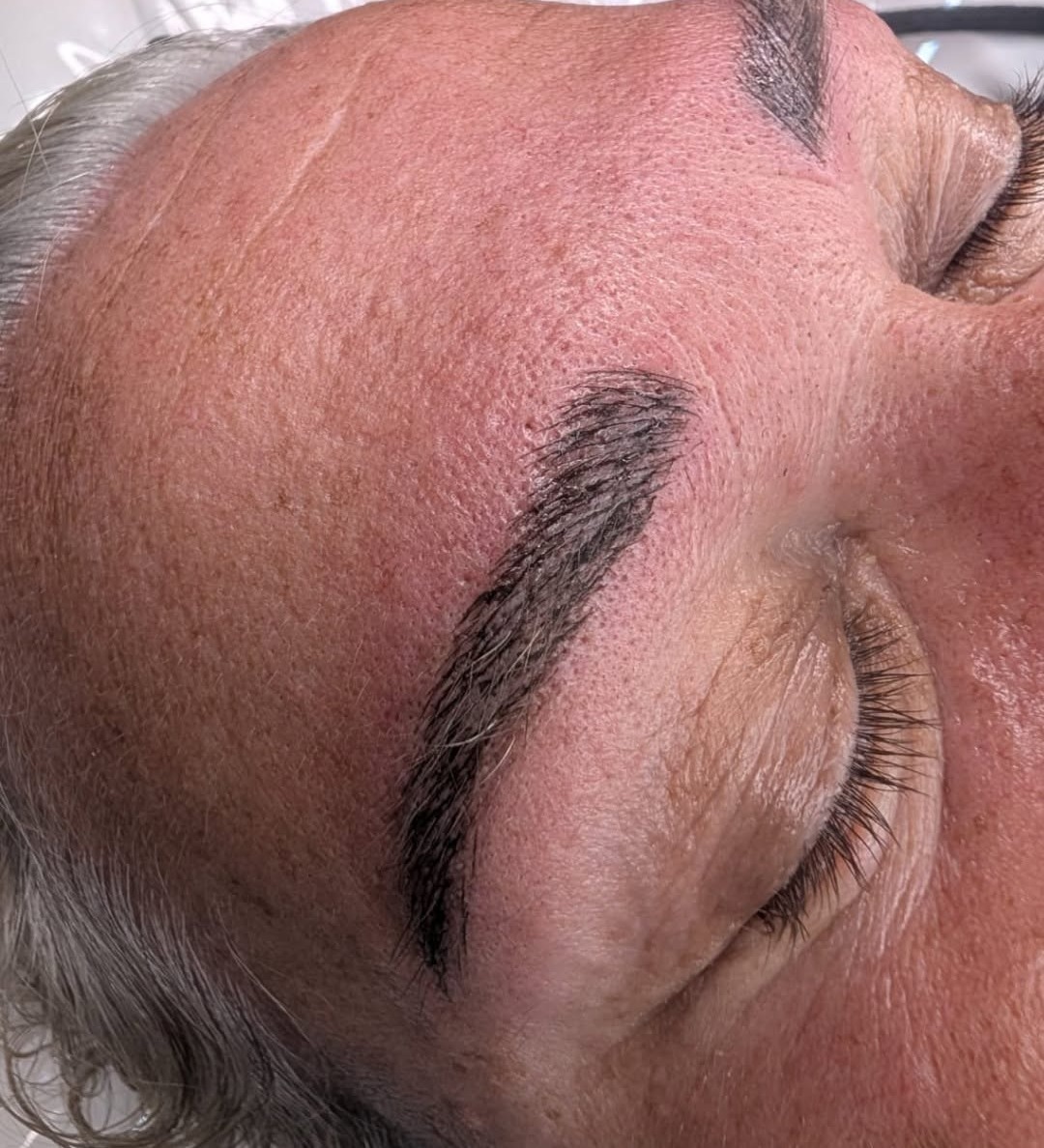 Freshly microbladed brows on a client with her eyes closed